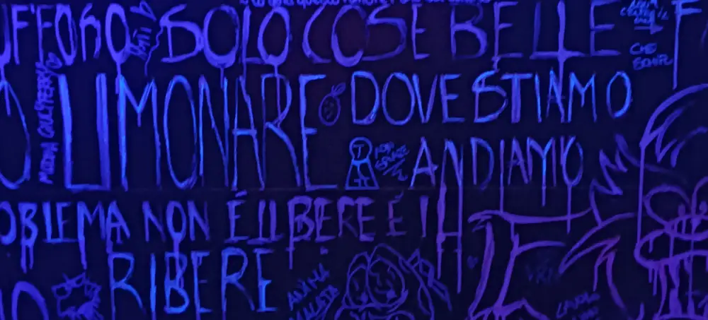 Scritte fluorescenti sul muro del bagno del 7COINS